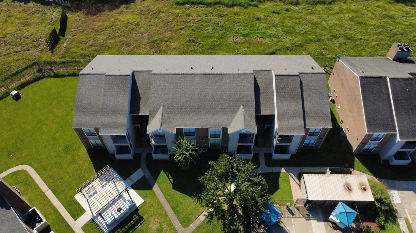 Aerial view of a finished shingle roof on a two-story multifamily building